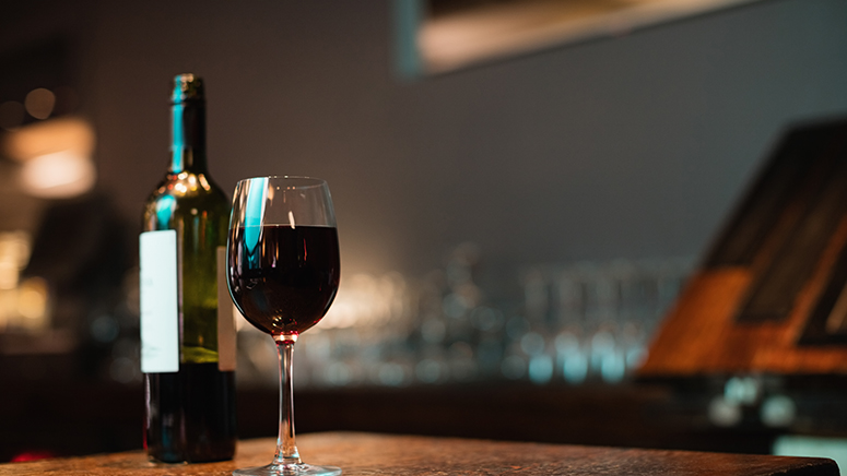 Glass of red wine and bottle on bar counter at bar